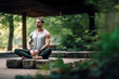 Young muscular man sitting and meditating outside in the nature