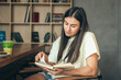 © puhimec - Attractive young woman is reading a book while sitting in a cafe.