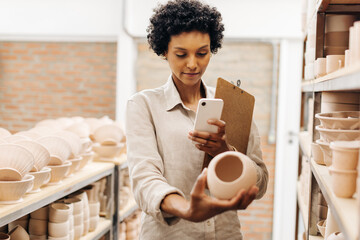 Female ceramist taking a picture of one of her earthenware products