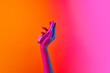 © Lustre Art Group  - Woman's hand holding vibrator, massager over yellow-pink background in neon light. Concept of toys for adult, healthy lifestyle