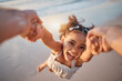 © Davids C/peopleimages.com - Girl child, spin and pov by ocean, portrait and smile for game, holding hands or speed in summer. Young female kid, parent and swing in air, sand or happy for family bonding, love or care in sunshine