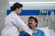 Indian doctor examining or checking admitted sick patient by using stethoscope at hospital ward - concept of Healthcare Professional, medical assessment and treatment.