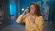 © kinomaster - A woman uses an asthma inhaler in the living room at home close up. Fight allergies, asthma. Home medicine concept.
