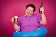 Funny fat man is engaged in vacation at sea drinking beer.