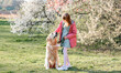 © Ievgen Skrypko - Girl petting golden retriever dog walking outdoors in spring park with blossom trees. Pretty female child kid with pet doggy labrador at nature with flowers in sunny day