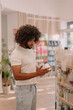 © ADDICTIVE STOCK - Black man with afro hairstyle reading label on bottle at pharmacy