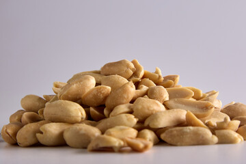 Wall Mural - Small handful of nutritious salted peanuts close-up on a white background is lined in a heap. Salty delicious peeled peanuts close-up, an appetizer with beer