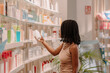 © ADDICTIVE STOCK - Black young woman with dreadlocks reading ingredients on medicine bottle label at pharmacy