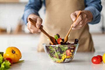 Cooking concept. Unrecognizable man in apron making fresh organic vegetable salad