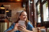 Fototapeta Londyn - Young woman using a smart phone in a cafe in london