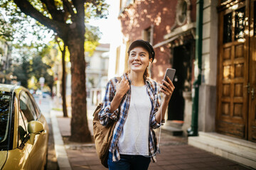 Young woman using a smart phone while walking on the sidewalk in a city