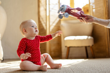 Wall Mural - Cute, adorable baby playing with airplane, sitting on floor in living room at home