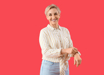 Wall Mural - Mature woman rolling up her sleeve on red background
