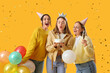 © Pixel-Shot - Female friends celebrating Birthday on yellow background