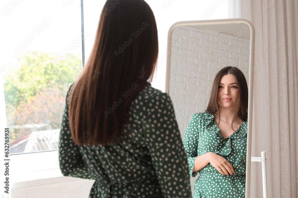 Young woman looking in mirror at home