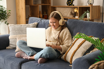 Poster - Little girl in headphones using laptop at home