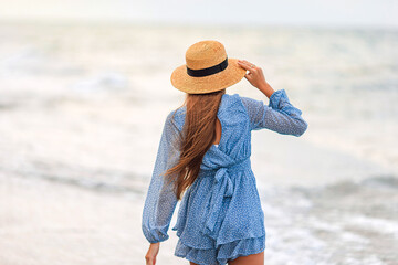 Wall Mural - Adorable young girl with beautiful long hair enjoy tropical beach vacation. The girl on the seashore at sunset