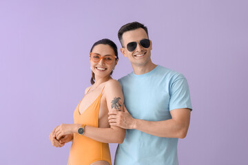 Sticker - Young couple in sunglasses on lilac background