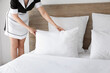 © Pixel-Shot - Chambermaid making bed in hotel room