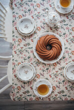 A vegan cake on a floral table with cups of tea
