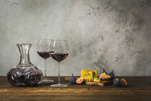Red Wine In Two Stemmed Glasses And Crystal Carafe With Blue Cheese And Figs