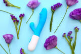 Composition with beautiful eustoma flowers and vibrator on blue background, closeup