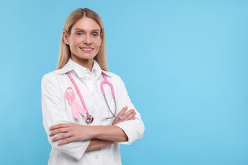 Poster - Doctor with pink ribbon and stethoscope on light blue background, space for text. Breast cancer awareness