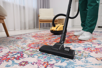 Canvas Print - Dry cleaner's employee hoovering carpet with vacuum cleaner indoors, closeup