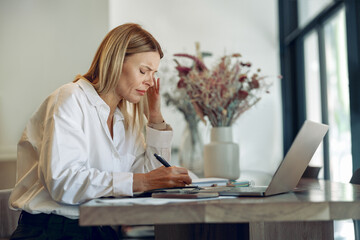 Wall Mural - Focused business woman working on laptop, making notes in cozy coworkign space interior