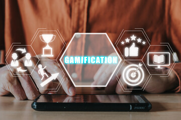 Gamification concept, Person hand using smart phone on desk with gamification icon on virtual screen.