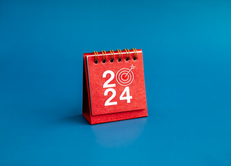 Poster - happy new year 2024 banner background. 2024 numbers year with target dart icon on red small desk cal
