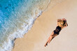 © Photo Sesaon - Aerial view of beautiful young woman in black swimsuit lying on sandy beach near blue sea with waves at sunset Summer vacation at Andaman Island