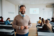 © Drazen - Happy university teacher in classroom looking at camera.