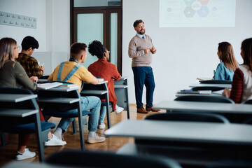 happy university professor giving presentation to group of students in lecture hall.