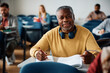 Smiling black senior man learning during adult education course and looking at camera.