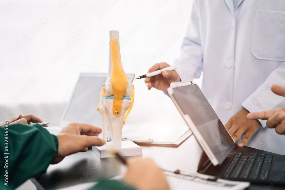 serious doctors team are analyzing fracture knee model showing the ...