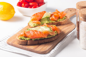 Two tasty open salmon sandwiches with avocado and cucumber. Morning healthy breakfast. Top view.