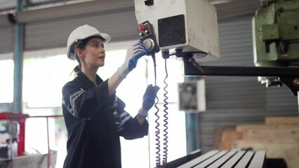 Wall Mural - Young smart woman engineer in safety helmet working with electronic heavy industry machine in lathe factory. Professional female technician factory worker control metal manufacturing industry 