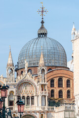 Wall Mural - View over decoration elements at facade roofs and cupolas of Basilica San Marco  in Venice, Italy, and old street lamp at blue sky