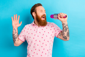 Portrait of overjoyed carefree person closed eyes hand hold microphone enjoy singing isolated on blue color background