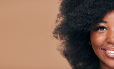 Wall Mural - Portrait, hair and mockup with a model black woman in studio on a brown background for natural cosmetics. Half face, smile and haircare with a happy afro female person on space for shampoo treatment