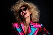 © Fred - Blonde young and happy woman laughing, wearing 80s fashionable stylish clothes. Posing as a supermodel on a black studio background
