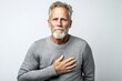 © Leon Waltz - Group portrait photography of a man in his 50s clutching his chest due to gastroesophageal reflux disease wearing a cozy sweater against a white background