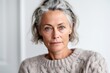 © Leon Waltz - Close-up portrait photography of a woman in her 40s with a hint of fatigue due to chronic kidney disease wearing a cozy sweater against a white background