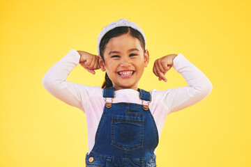Smile, portrait and girl child with arm flex in studio for confidence, strong and power on yellow background. Happy, face and excited kid with bicep strength, pose or empower, positive or growth sign