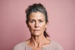 © Leon Waltz - Medium shot portrait photography of a woman in her 40s with a somber and deeply sad expression due to major depression wearing a simple tunic against a pastel or soft colors background