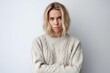 © Leon Waltz - Medium shot portrait photography of a woman in her 30s visibly in discomfort and fatigue from an autoimmune disease like lupus wearing a cozy sweater against a white background
