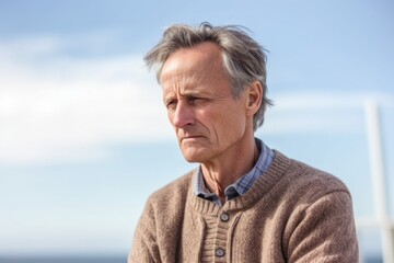 Medium shot portrait photography of a man in his 50s visibly in discomfort and fatigue from an autoimmune disease like lupus wearing a chic cardigan against a sky background 