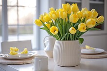 Gorgeous Arrangement Of Yellow Tulips Displayed In A Vase On The Dinner Table In A White Kitchen With Well Lit Interiors At Home.
