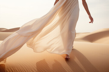 Woman in a long dress walking in the desert with flowing fabric in the wind